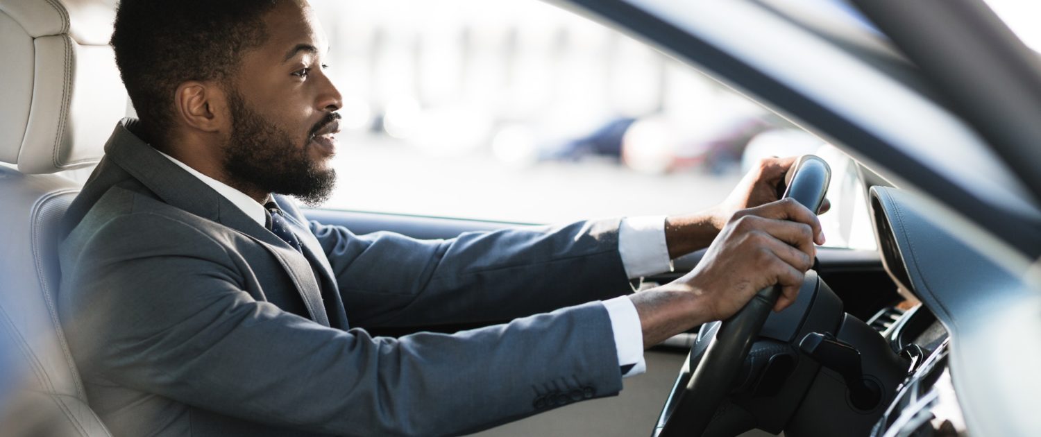 Driving with pleasure. Afro man in formalwear driving car