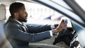 Driving with pleasure. Afro man in formalwear driving car